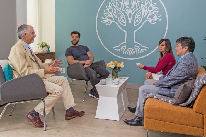 Group of four sitting down and having a joyful conversation about transcendental meditation.